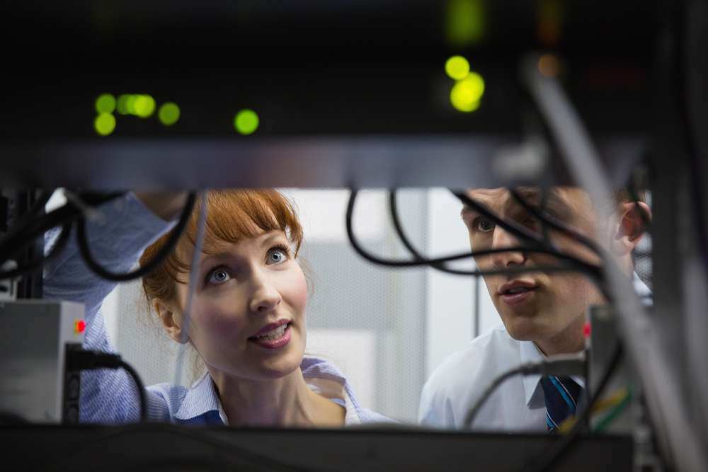 Team of technicians talking and looking at server in large data center